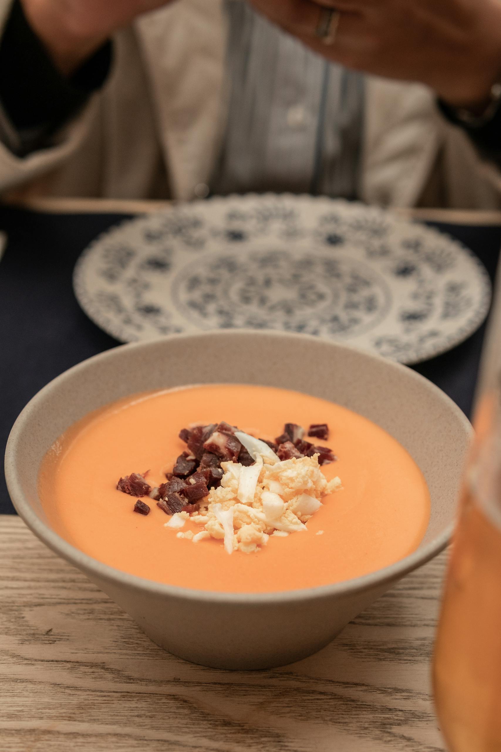 Delicious salmorejo served in a ceramic bowl, topped with ham and egg, perfect for traditional Spanish cuisine lovers.