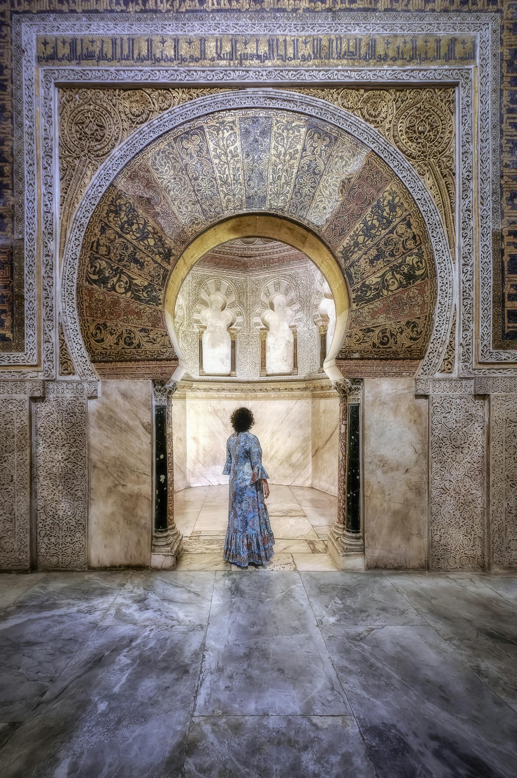 Woman standing inside Mezquita-Catedral de Córdoba, Spain, admiring the intricate interior arch.